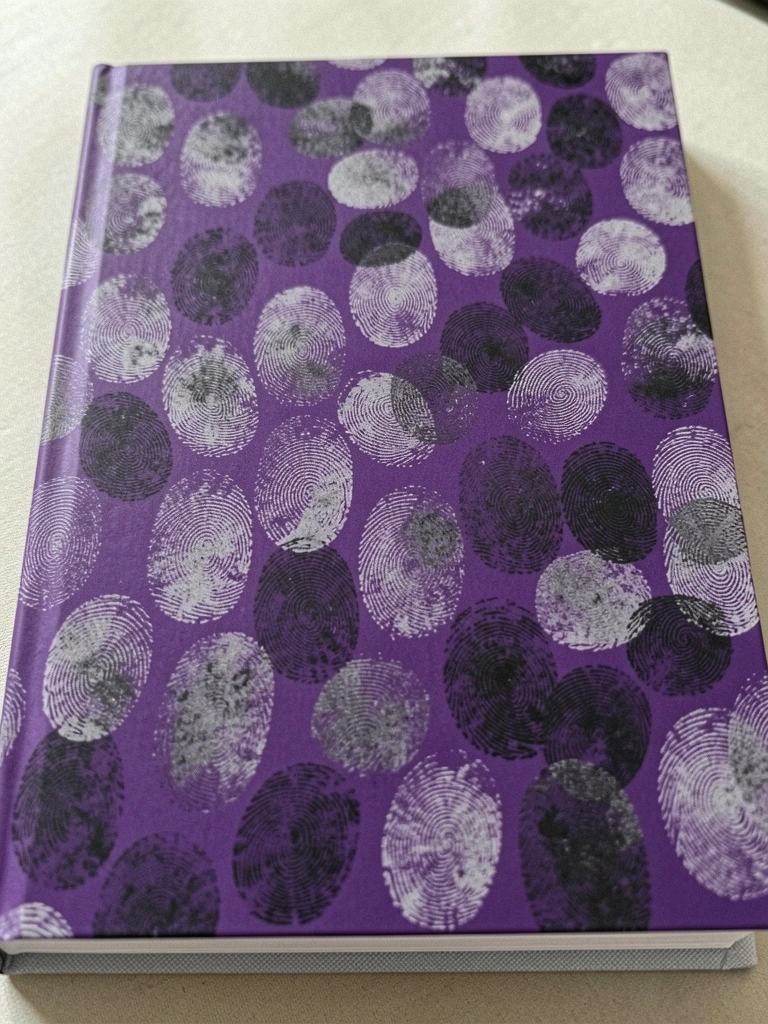 Pessoa folheando um caderno com anotações ao lado de um notebook sobre uma mesa de madeira.